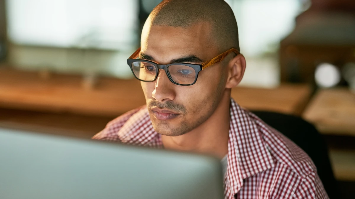 Man looking at desktop screen in dim room